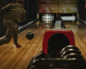 a man rolls a bowling ball down the alley toward the pins