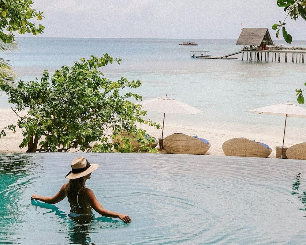 Person in a resort pool overlooking a beach.