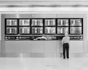 a man looks at flight information boards at an airport