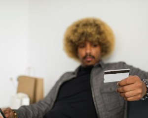 a man sits on a couch looking at a credit card
