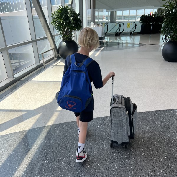 A photo of a child walking through an airport with luggage.