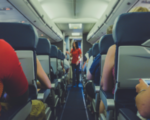 looking up the aisle of a crowded plane toward a flight attendant in the aisle near the cockpit