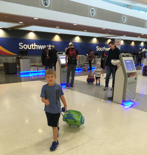 A photo of a child pulling a suitcase in front of a Southwest ticket counter