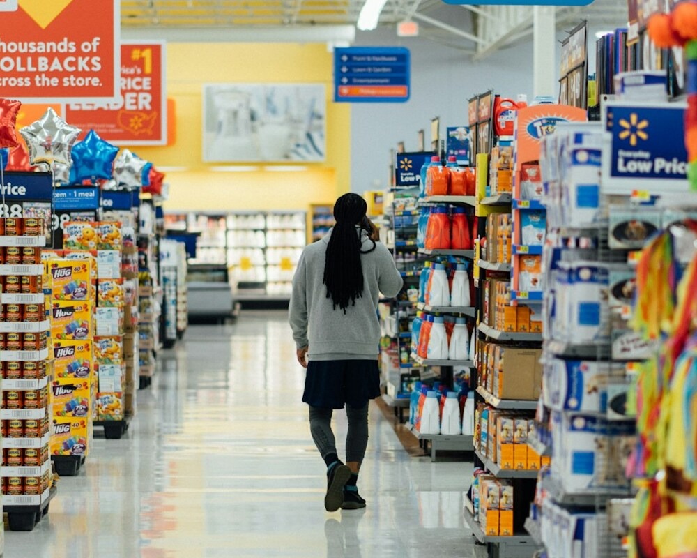 A person on the phone while walking in a Walmart grocery aisle.