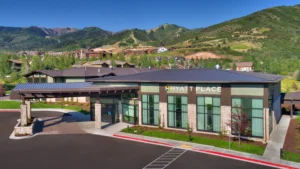 Hyatt Place hotel inthe front with green mountains and brown hotels and houses in the background.