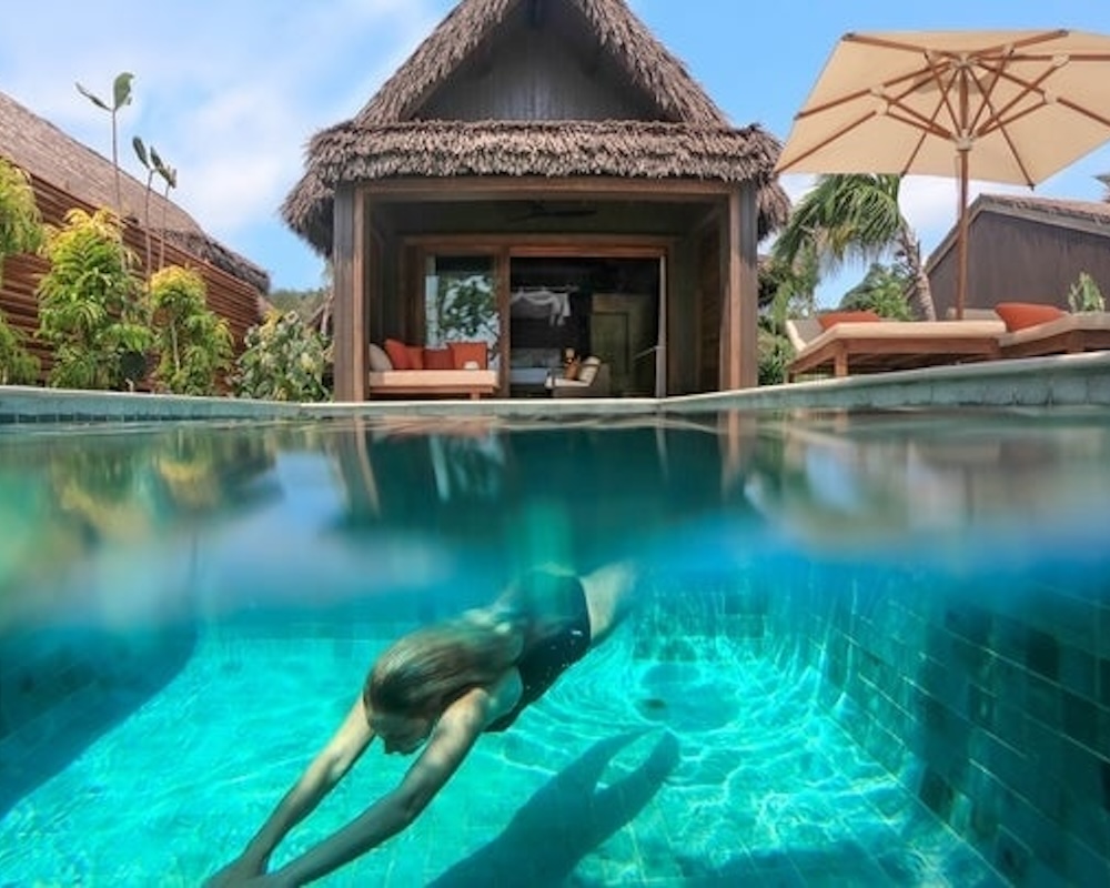 Woman diving into a pool near a villa at the Six Senses Fiji.