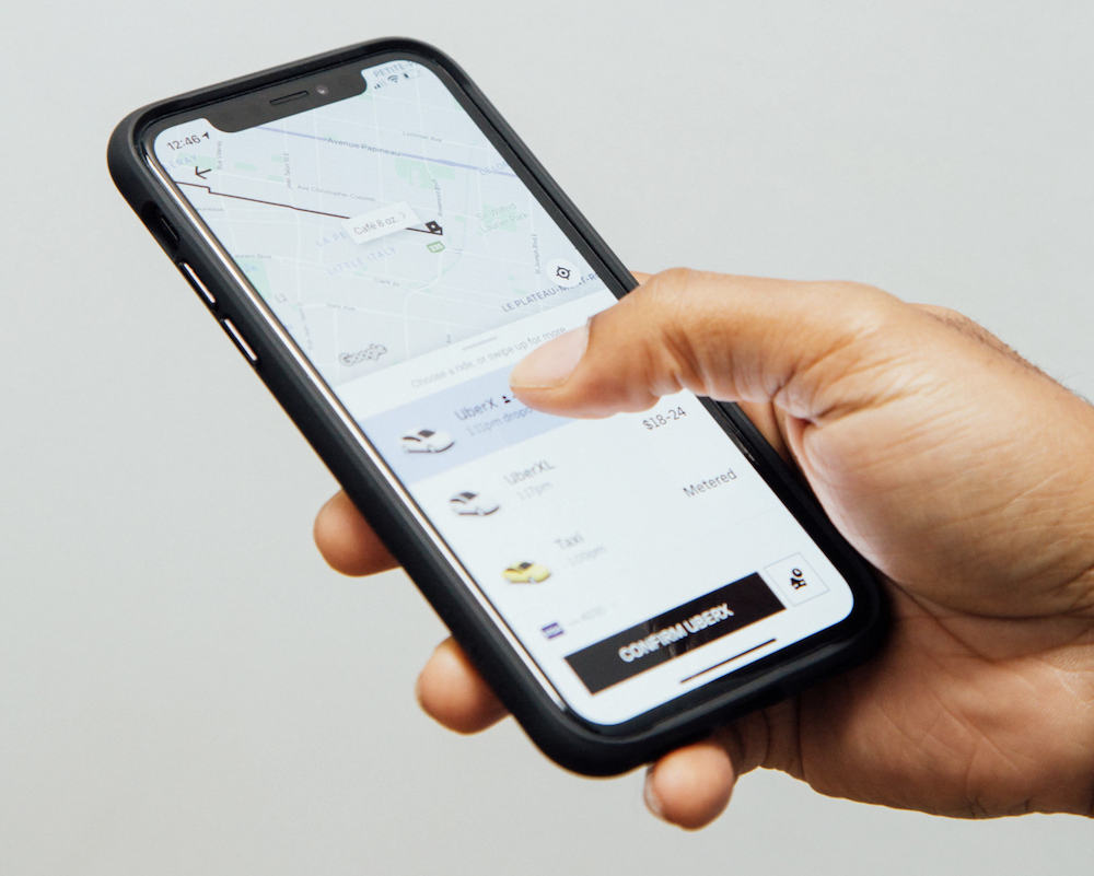 Person holding a phone displaying the Uber app.