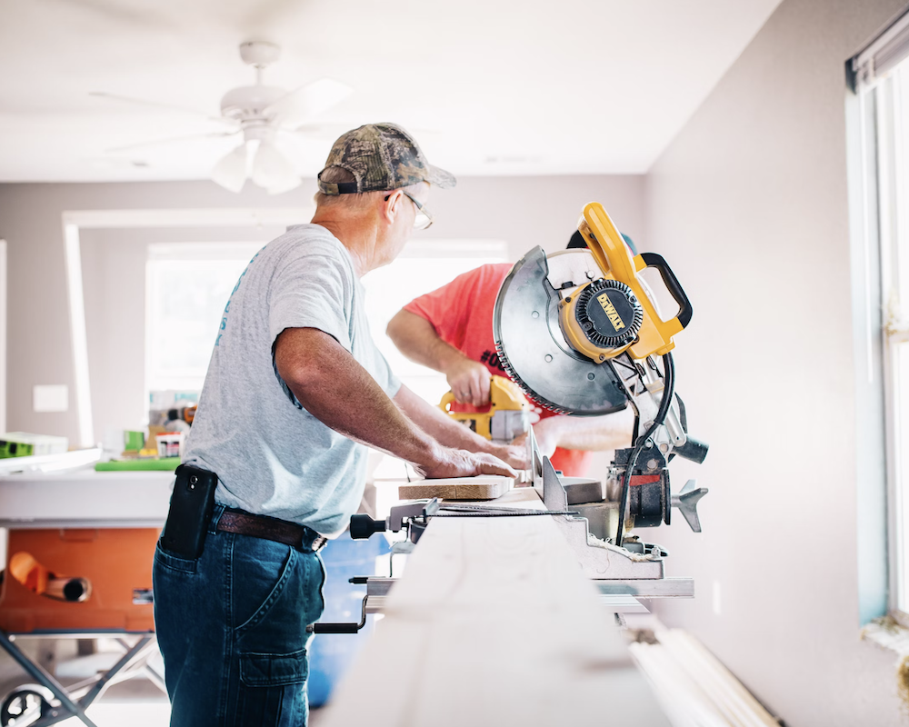 Two people working a circular saw indoors.