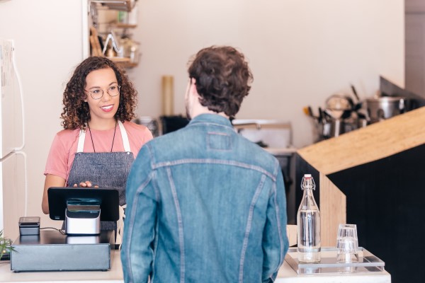 A photo of a barista, chatting with a customer at the cash register