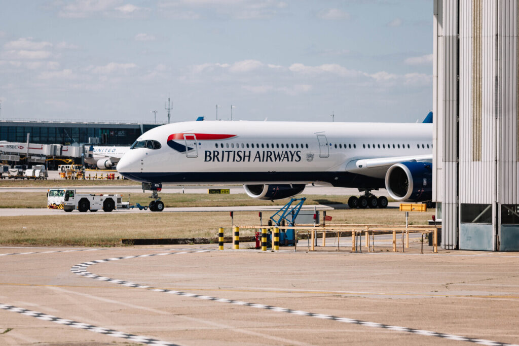 A British Airways Airbus A350 taxiing to a gate at an airport.
