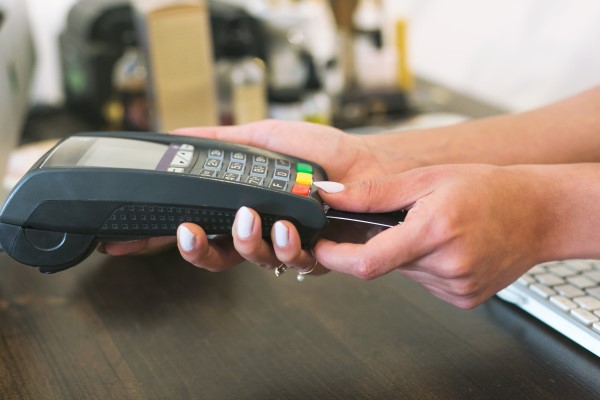 A photo of a woman's hands inserting a credit card into a reader