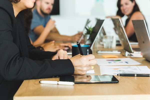 Photo of a business meeting with several attendees on laptops