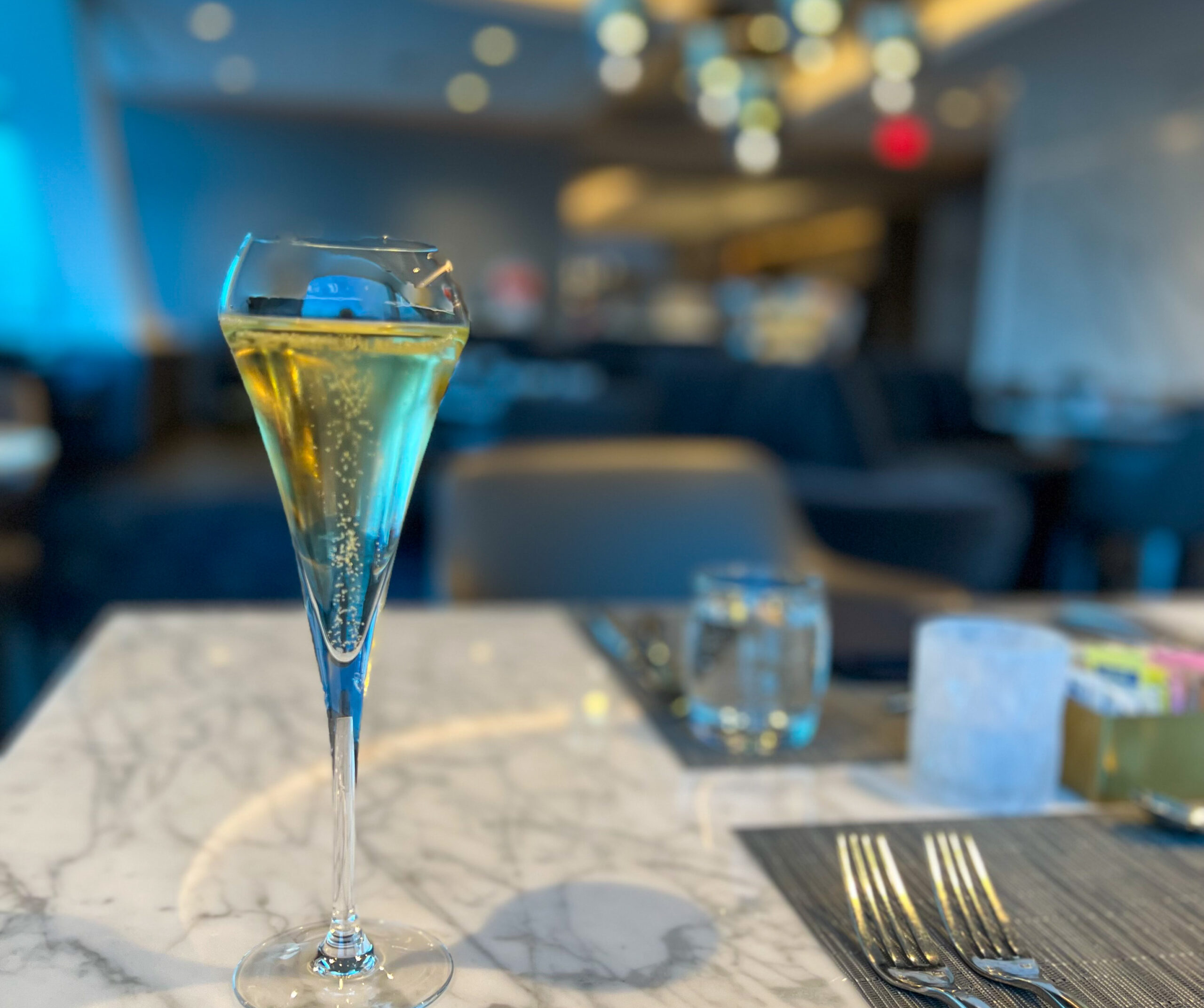 A glass of champagne sitting on a table at the United Polaris Lounge in San Francisco