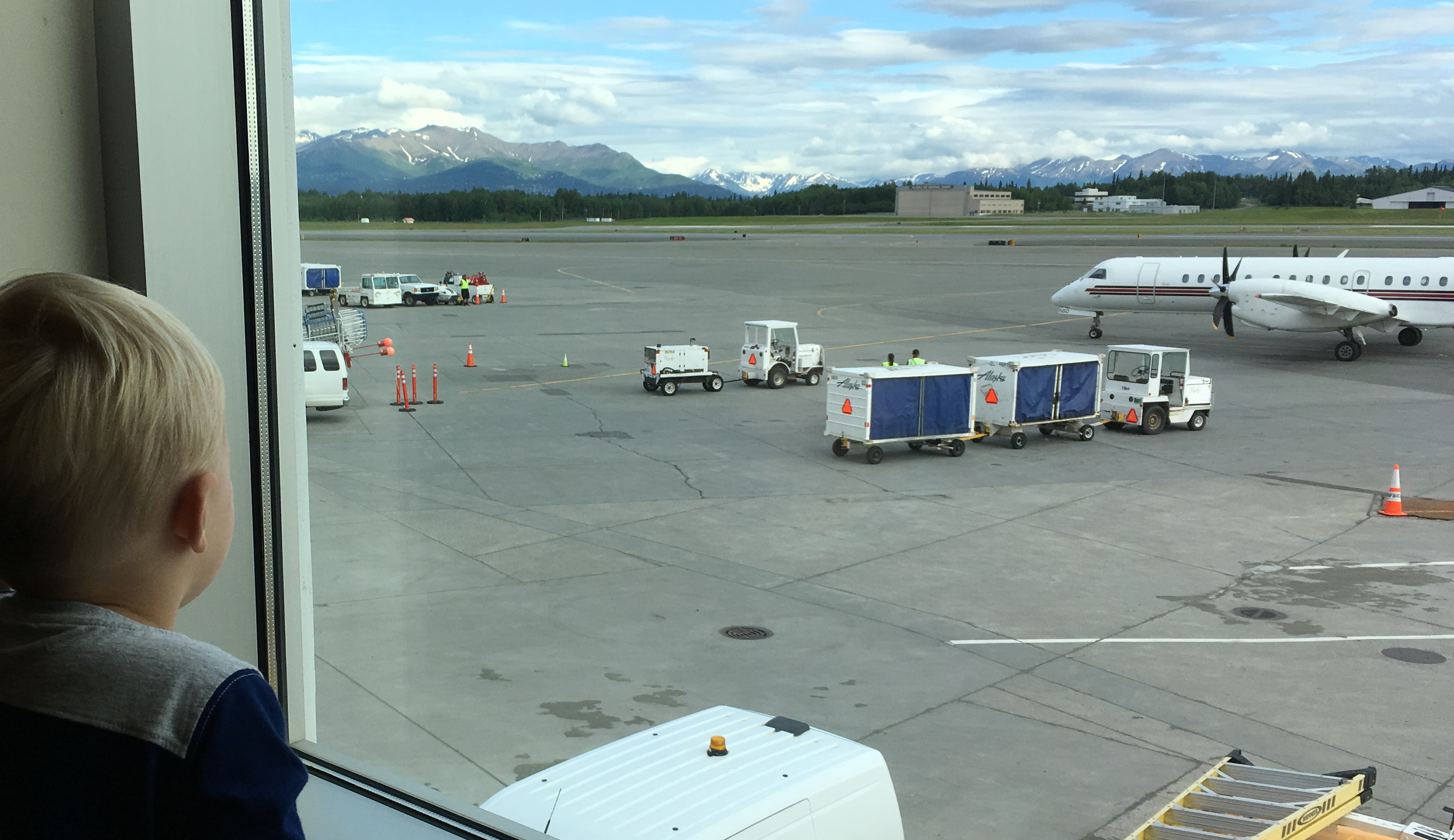 A child looking out of the window at an Alaska Airlines plane