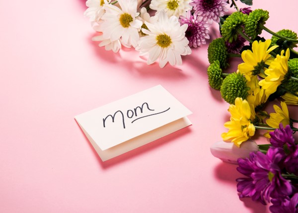 A photo shows a card that says Mom and some flowers