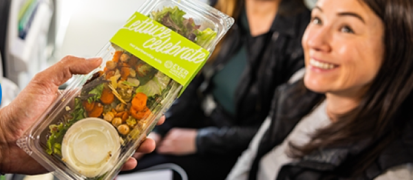 A flight attendant handing a salad to a passenger on an flight