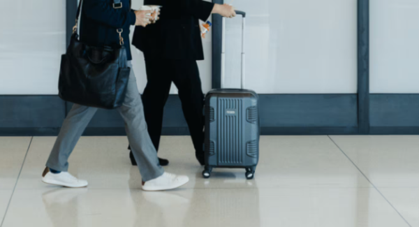 A photo shows two people walking in an airport with luggage