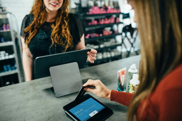 A woman pays at a store checkout terminal