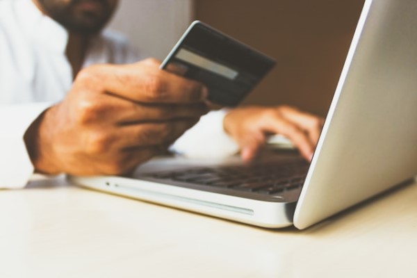 A man is holding a credit card while searching online
