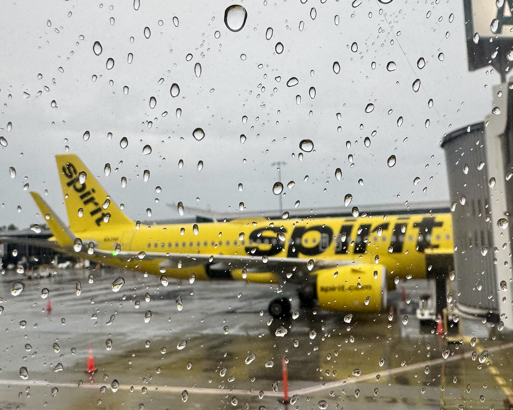 Spirit Airlines A320 jet parked at a gate -- as seen from the rainy window of another Spirit plane.