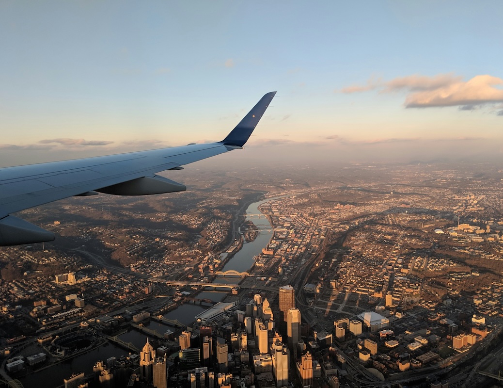 an airplane wing flying over a city