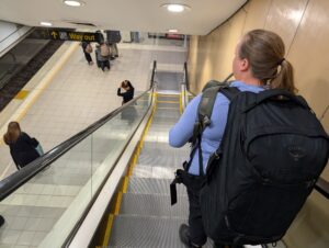 Woman wearing Osprey backpack on escalator in train station