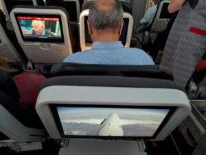 Turkish Airlines economy passenger leaning forward to eat a meal while seatback is reclined