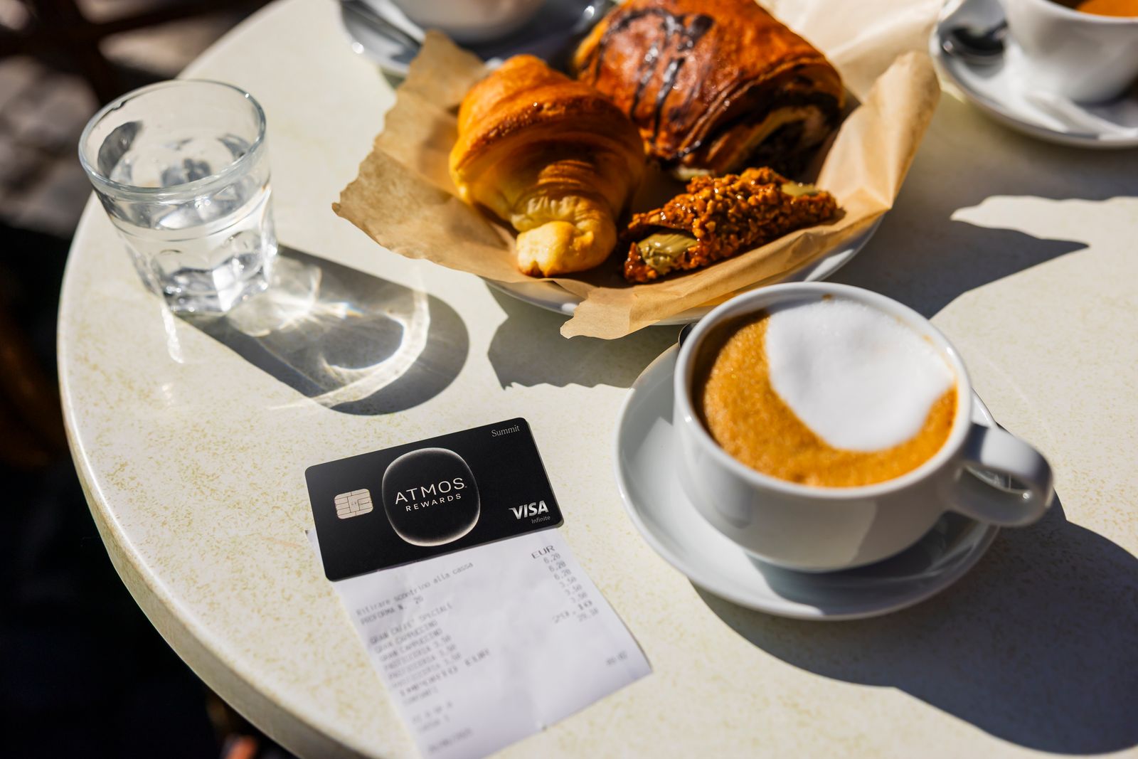 Atmos Summit Visa on a table surrounded by coffee and pastries