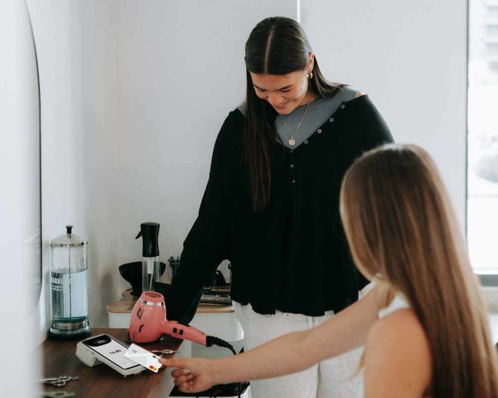 Woman paying a hair stylist with a credit card.