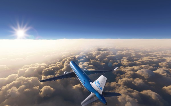 A photo of a KLM plane that is flying above the clouds.