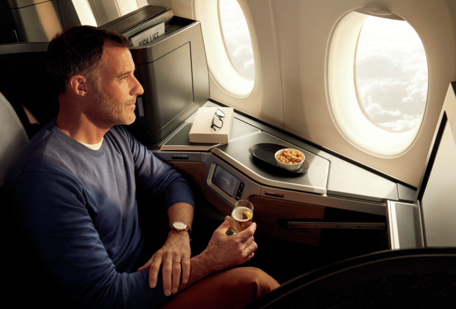 A passenger seated in British Airways' Club World business class holding a drink