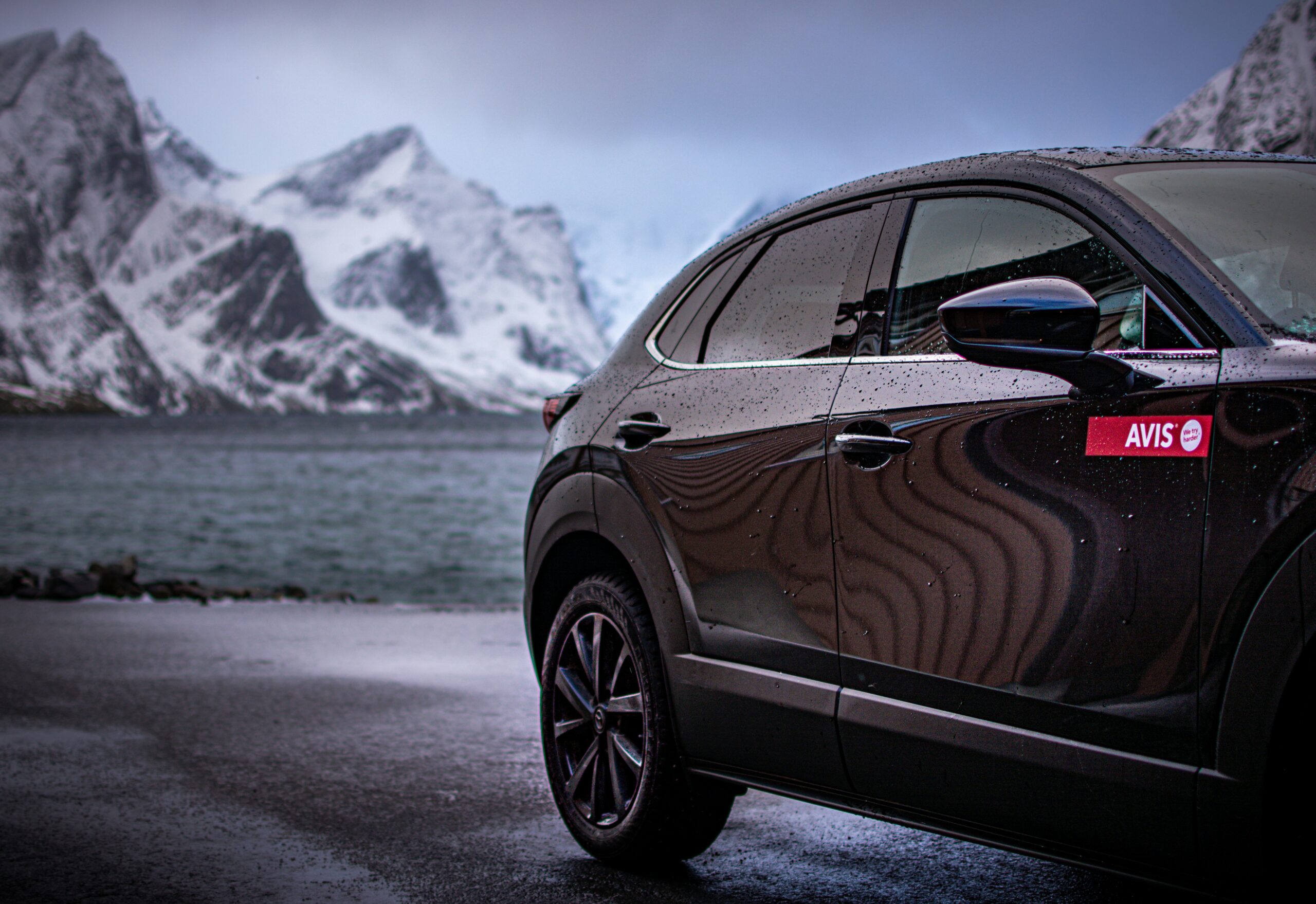 A rental car in front of a lake with snow-capped mountains