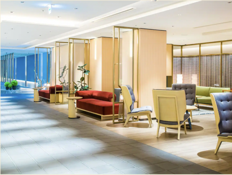 Interior of a hotel lobby with tan chairs, burgandy sofas, and peach-colored dividers