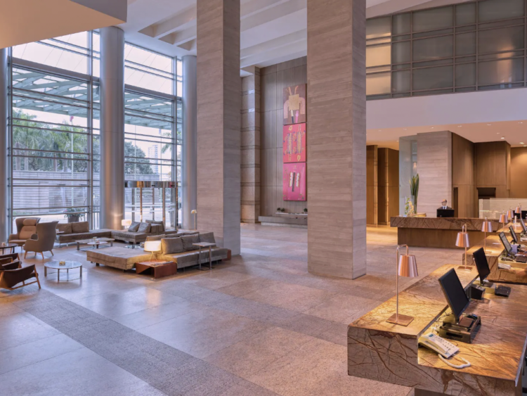Large hotel lobby with tall ceilings, pillars, couches, and lamps 