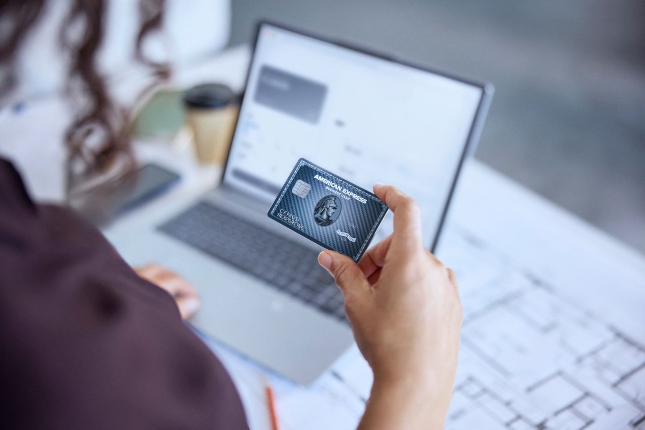 Holding the American Express Graphite™ Business Cash Unlimited Card in front of a laptop