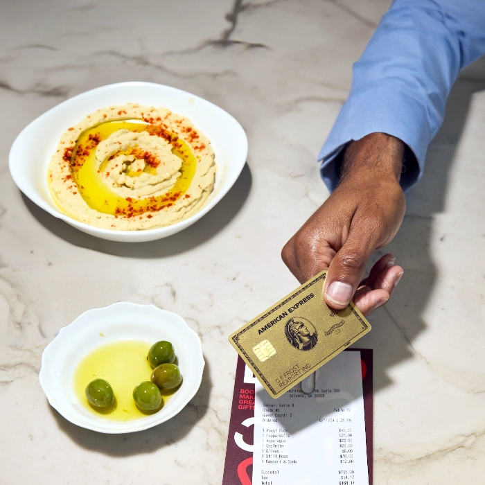 Someone paying a restaurant bill with an Amex Gold Card