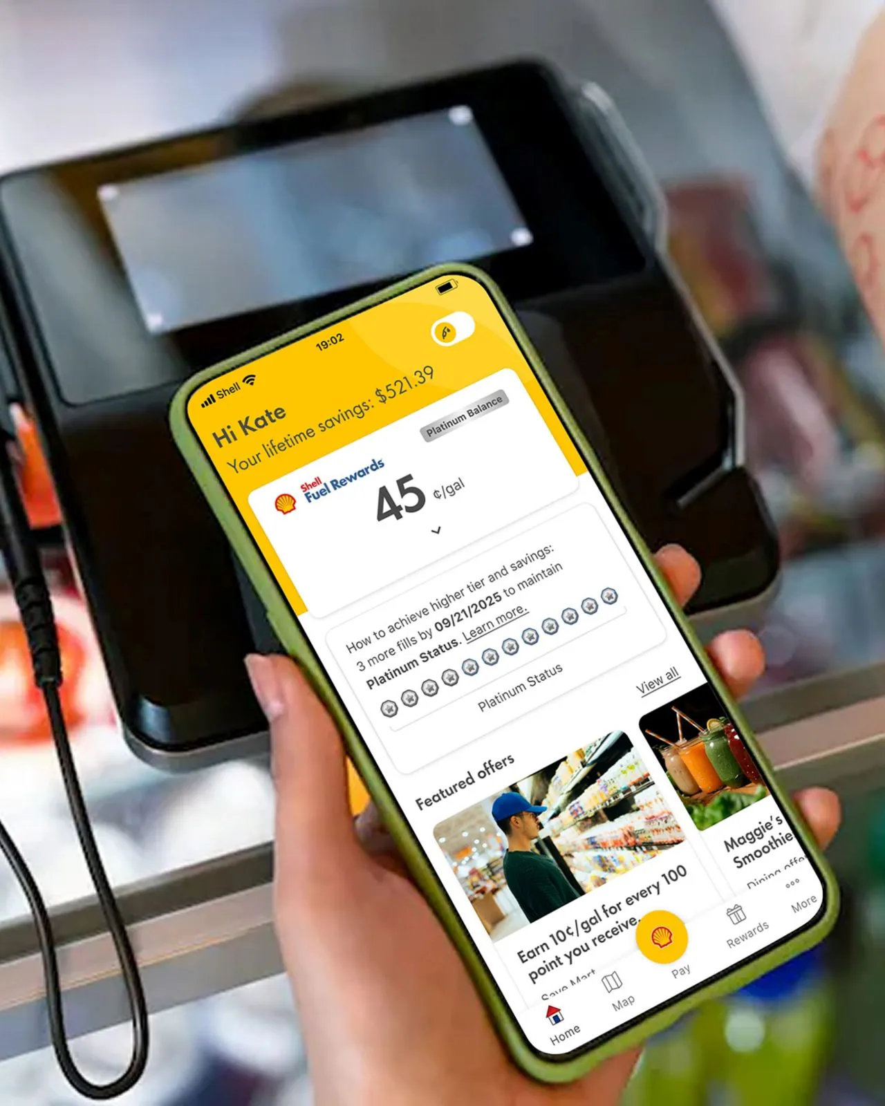 Close-up of a hand holding a smartphone with the Shell Fuel Rewards app open, displaying the available fuel rewards discount