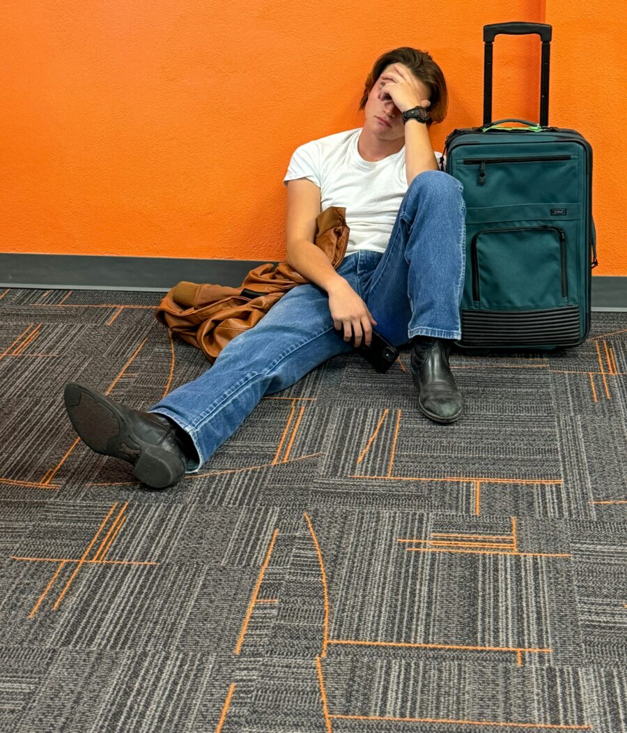 Man sitting on airport floor with hand over his face