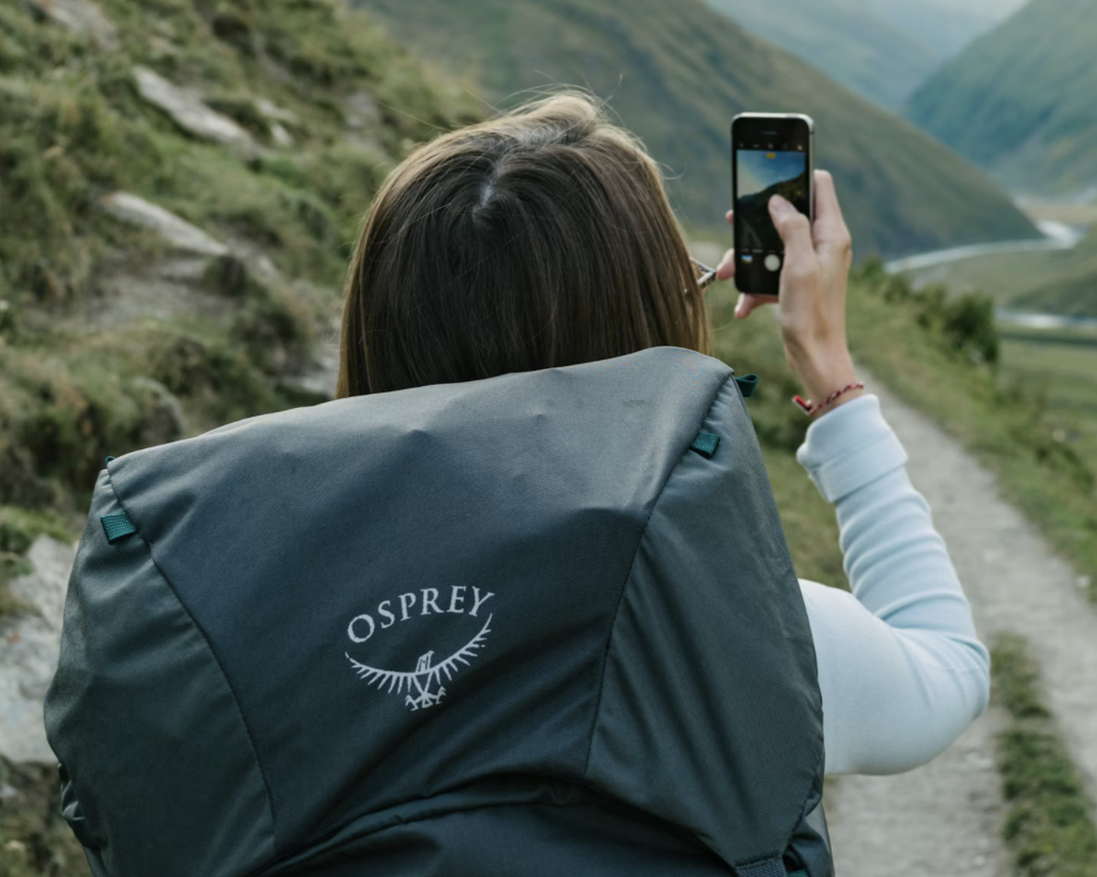 Mountain Backpacker Woman with backpack making photo on iPhone