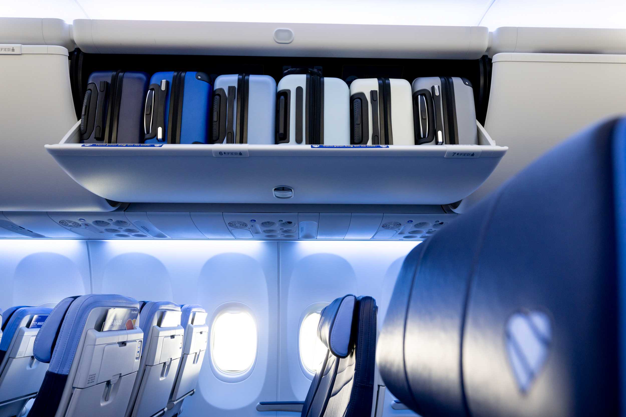 Southwest interior focused on an overhead bin full of luggage
