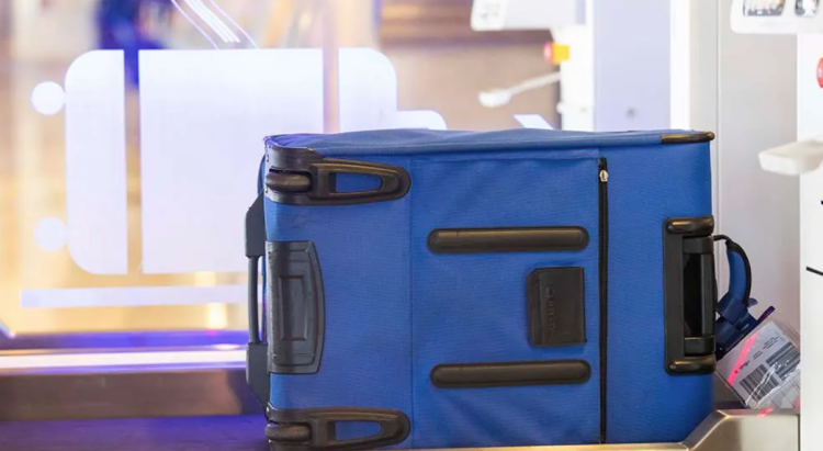 A photo of a blue suitcase going through a scanner