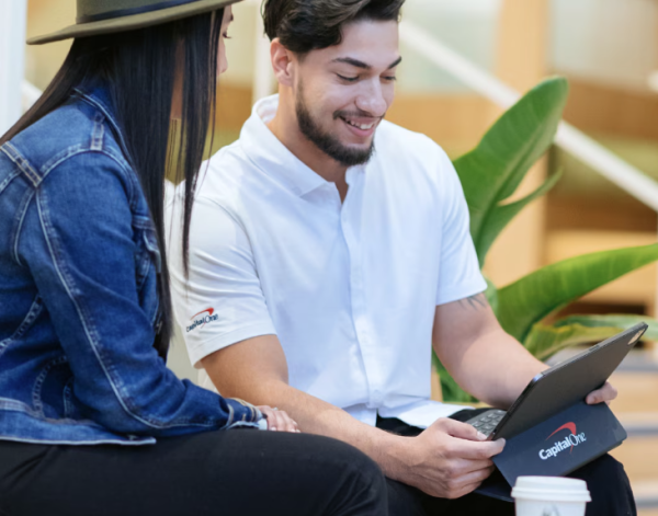 A Capital One mentor meeting with a woman, looking at an iPad together.