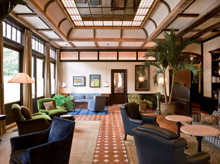 The Greenwich Hotel lobby with cozy chairs, greenery, and lots of natural lightening. 