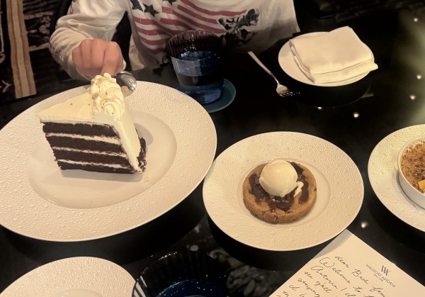 A slice of layered red velvet cake, a warm cookie a la mode,and a fork about to cut into the cake.