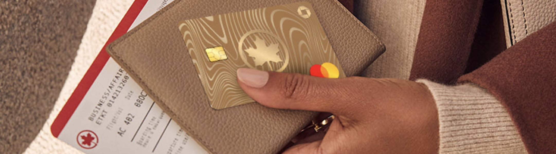 Person holding the new Aeroplan Card on a passport with a plane ticket