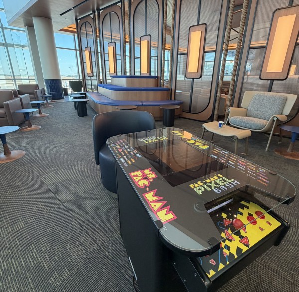 A room with a Pac-Man arcade game, seating, and a glass wall.