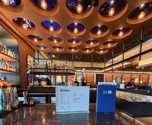 A cocktail lounge-styled bar with a menu standing on the counter. There is recessed purple and amber lighting.