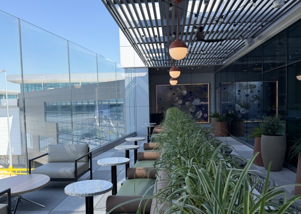 A outdoor terrace at the United Club shows plants, and seating overlooking the tarmac.
