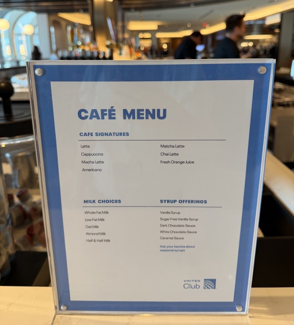 A menu displays coffee options on the counter of a bar.