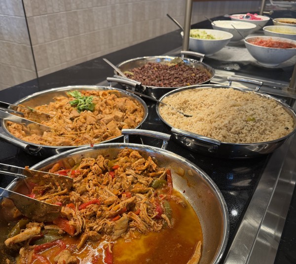A buffet spread with meat, rice, beans and bowls of taco fixings.